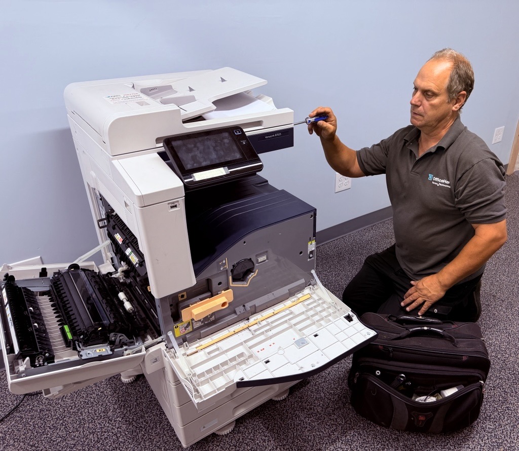 In-house Xerox copier repair technician on a customer service call Advantage Business Systems technician repairing a Xerox VersaLink multifunction copier on site in Connecticut, front doors open at the fuser and transfer belt.